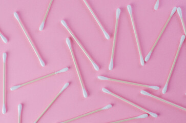 Scattered cotton swabs on pink background in chaotic arrangement