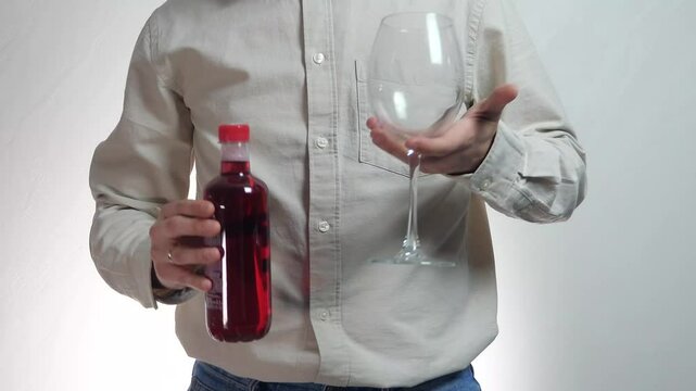 Close-up of male hands holding empty glass and bottle of red alcohol (wine), looking at it and then throwing it aside and waving finger no. 