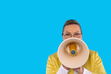 Woman in yellow jacket holds megaphone against bright blue background promoting a message with...
