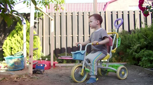 Child riding tricycle in backyard garden