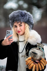 Portrait of a young beautiful blonde model-looking girl in winter clothes and a fur hat in winter.