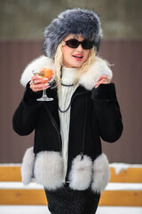 Portrait of a young beautiful blonde model-looking girl in winter clothes and a fur hat in winter.