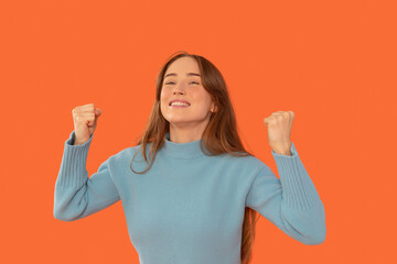 Excitement fills the air as a woman joyfully celebrates success in front of a vibrant orange...