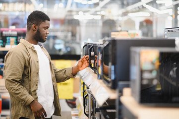An African-American man is choosing a new microwave oven at an electronics store