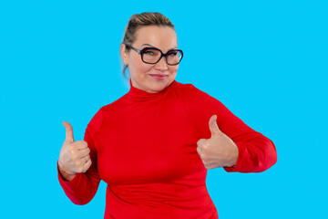 Woman in red long-sleeve top gives thumbs up gesture against a bright blue background
