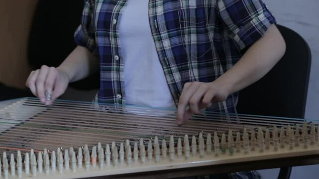 Close-up of a musician's hands playing a traditional string instrument, likely a kanoon. The intricate captures the essence of classic Middle Eastern music during a cultural performance.