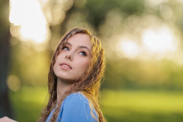 Beautiful Girl with long hair posing in sunbeams in park