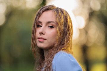 Naklejka premium Beautiful Girl with long hair posing in sunbeams in park