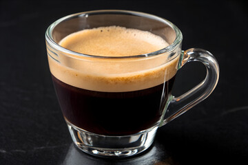 Freshly brewed espresso in a clear glass cup rich crema on top perfect for morning coffee or cafe advertising