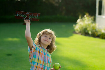 Child playing. Happy kid playing with toy paper wings outdoors in summer field. Travel and kids vacation concept. Imagination and freedom.