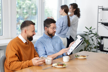 Colleagues eating and discussing work during lunch break in office
