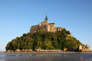 view of famous Le Mont Saint-Michel tidal island with clear water and beautiful reflections on a sunny day, Normandy, northern France