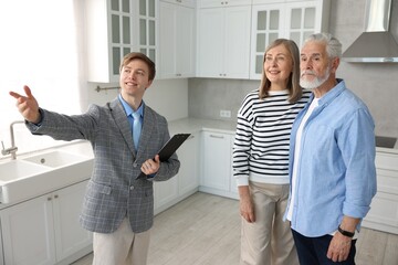 Smiling real estate agent showing apartment to couple indoors