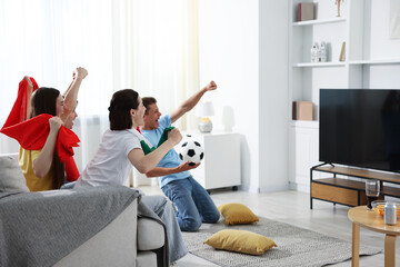 Emotional football fans watching game together indoors
