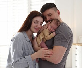 Happy parents with their cute newborn baby indoors