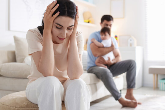 Woman suffering from postpartum depression and her husband with baby at home, selective focus