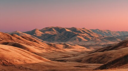 Naklejka premium A panoramic view of a mountain range from atop a hill, with a rosy-pink and azure sky as the backdrop