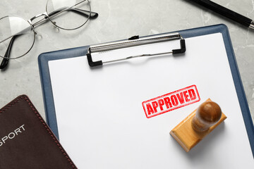 Sheet of paper with red stamp Approved, passport and wooden stamp on table, closeup