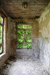 völlig verfallener Innenraum in Bauruine mit abbröckelndem Putz und abblätternder Farbe Blick nach außen durch Fenster
