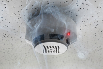 Fire alarm system detector on ceiling triggered by smoke