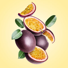 Delicious ripe passion fruits and green leaves falling on pale yellow gradient background