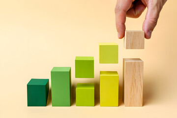 Hand placing wooden block on growing green and yellow bar graph