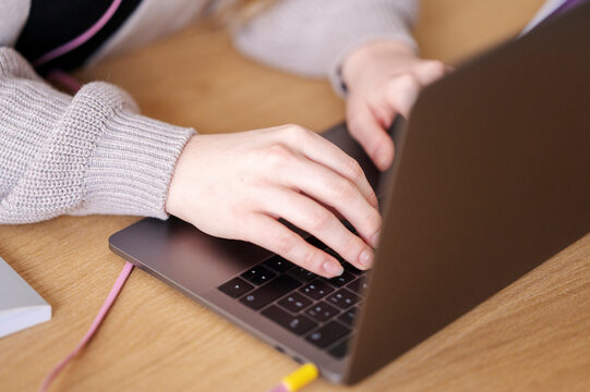 A person is typing on a laptop. They are likely working or studying, using the computer to complete a task.