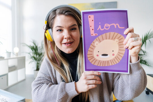 A teacher is showing a lion flashcard during an online lesson. She's using visuals to help kids learn the alphabet and new words.