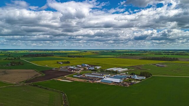Large plantation and farmland landscape in Europe with crops growing in cultivated fields under a cloudscape aerial time apse