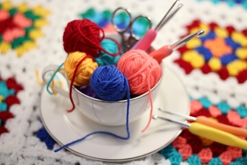 A cup and a saucer with clews balls of yarn wool and crocheted blanket handmade craft bright photo