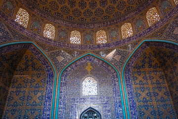 Intricate Islamic tilework and Quranic inscriptions inside a historic mosque in Esfahan, Iran, showcasing Persian architecture and spiritual artistry.