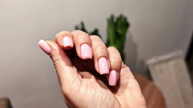 Close-up of a hand with freshly manicured nail having glossy, pale pink polish