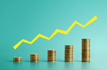 Stacks of gold coins increasing in height with a yellow upward arrow line symbolizing financial...