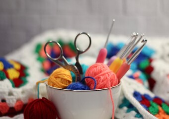 A cup and a saucer with clews balls of yarn wool and crocheted blanket handmade craft bright photo