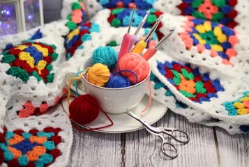 A cup and a saucer with clews balls of yarn wool and crocheted blanket handmade craft bright photo