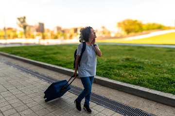 Digital nomad walking with luggage in urban park