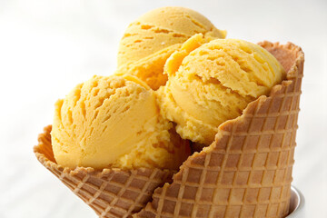 Mango ice cream scoops in a waffle cone.