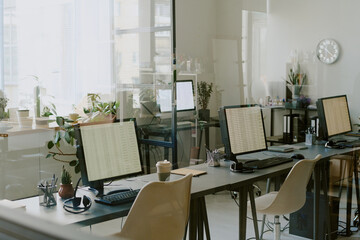 Empty office environment with several workstations set up, featuring computers, plants, and office supplies, reflecting clean and organized workspace