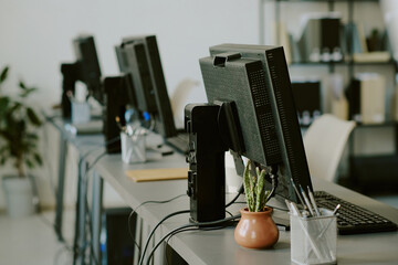 Multiple computer stations set up in modern office environment featuring organized workspaces,...