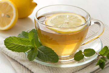 Cup of Herbal Tea with Lemon and Fresh Lemon on White Table