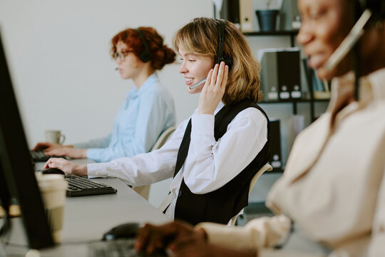 Group of diverse call center agents working with headsets, engaged in customer service tasks. Multiethnic team focusing on calls, providing assistance and solutions