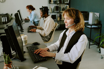 Office environment with diverse team handling customer service tasks using technology and collaboration tools wearing headsets and engaging in their jobs