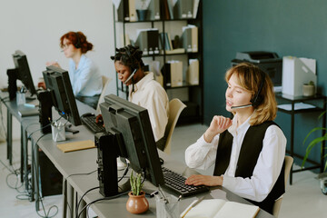 Diverse team working at call center with headsets, actively engaging with customers at modern workstations. Vibrant office ambiance with vocal interactions and computer usage