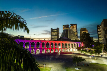 Lapa Aqueduct Illuminated With Purple and Pink Colors in the Evening With Tall Office Buildings of Rio de Janeiro Downtown