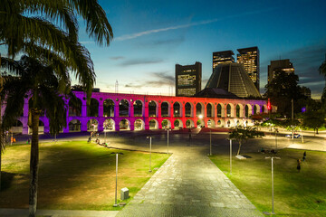 Lapa Aqueduct Illuminated With Purple and Pink Colors in the Evening With Tall Office Buildings of Rio de Janeiro Downtown