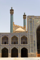 The stunning architecture of the Shah Mosque in Isfahan, Iran, featuring intricate tile work and towering minarets against a clear sky.