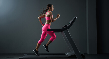 Young woman running on treadmill in gym during evening workout  
