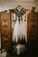 Black and White Gothic Lace Wedding Dress Hanging on Vintage Armoire