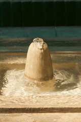 Close-up of a traditional Persian stone fountain bubbling gently in sunlight, showcasing the serene charm of historic Iranian garden architecture.