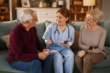 A home medical care provider discusses medication with an elderly couple on a comfortable couch....